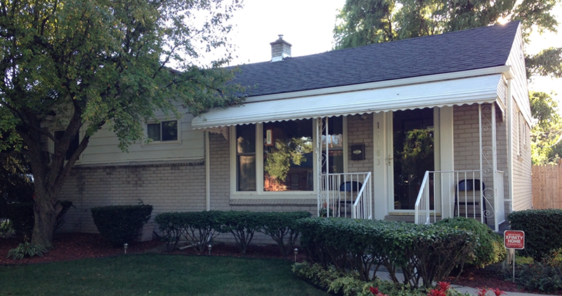 A house with a porch and awning in the front yard.