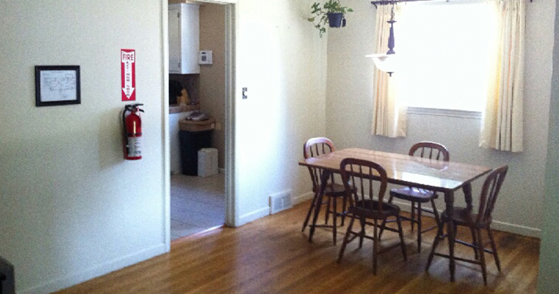 A dining room with wooden floors and white walls.