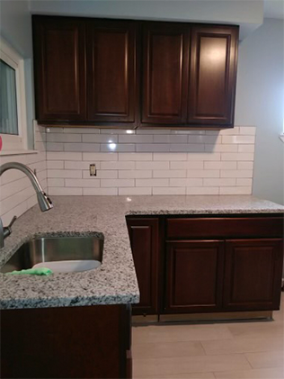 A kitchen with white cabinets and granite counter tops.