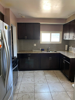 A kitchen with brown cabinets and white tile floor.