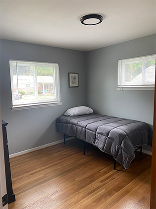 A bedroom with a bed and two windows.