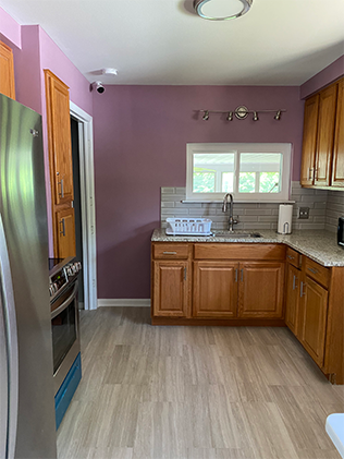 A kitchen with wooden cabinets and wood floors.