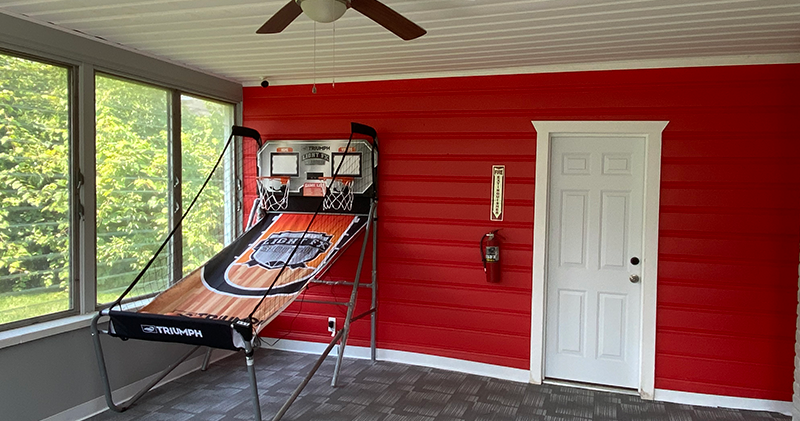 A red wall with a basketball hoop and a door.