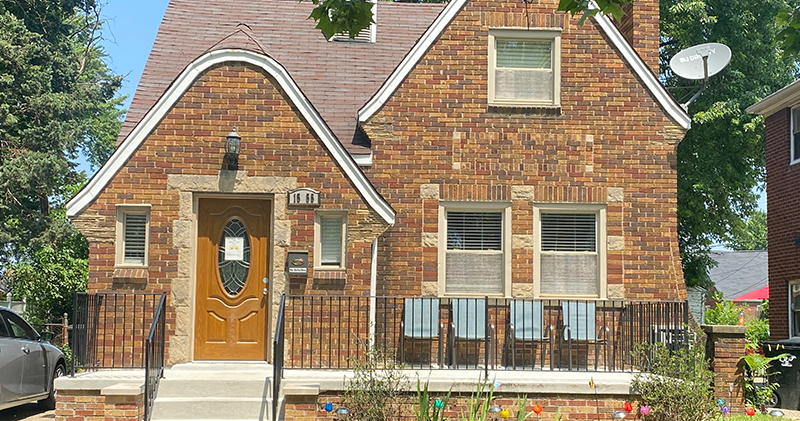 A brick house with a brown door and white trim.