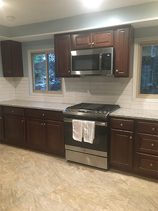 A kitchen with brown cabinets and white tile.