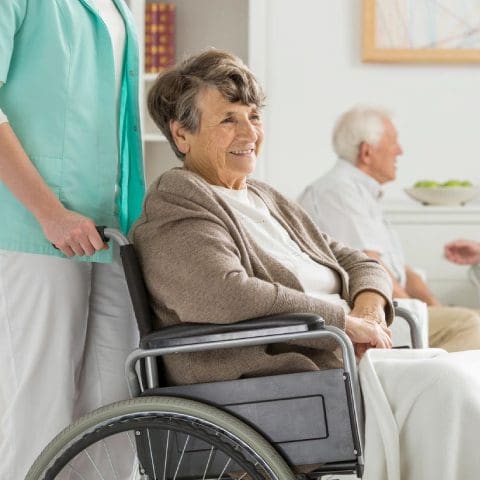 A woman in a wheel chair with two other people.