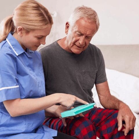 A nurse showing an older man something on his tablet.