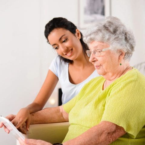 A woman and an older person looking at something on the screen.