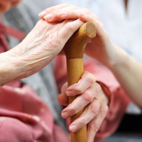 A person holding onto the handle of a cane