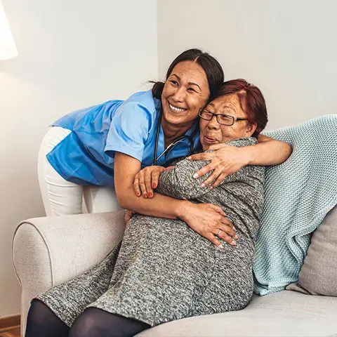 A woman hugging an older lady on the couch